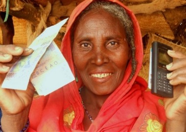 Lady holding cash transfers re-loadable card and a telephone